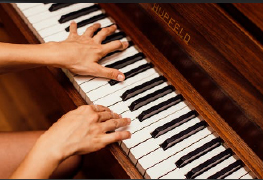 Handen die pianospelen op een bruin houten piano